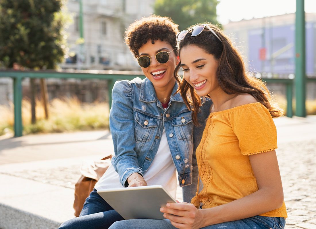 Read Our Reviews - Friends Smiling and Laughing Outdoors in Portland While Viewing a Tablet